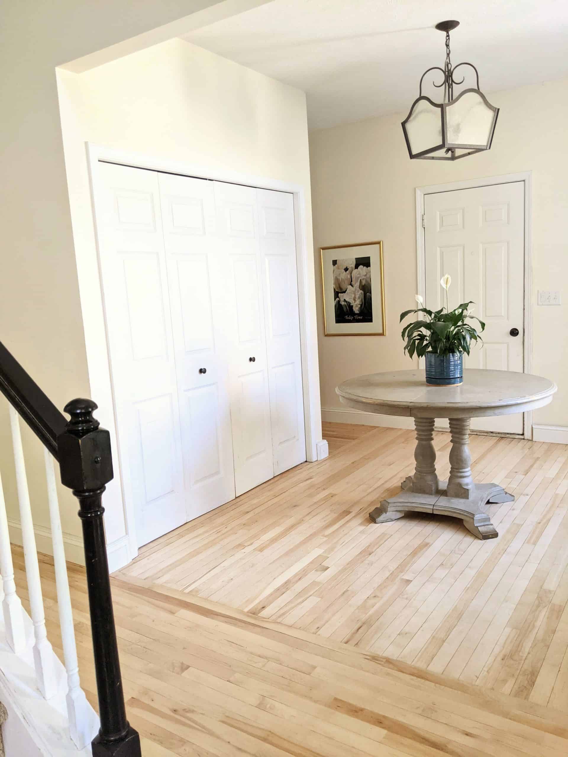 foyer with light maple floors and table at the center