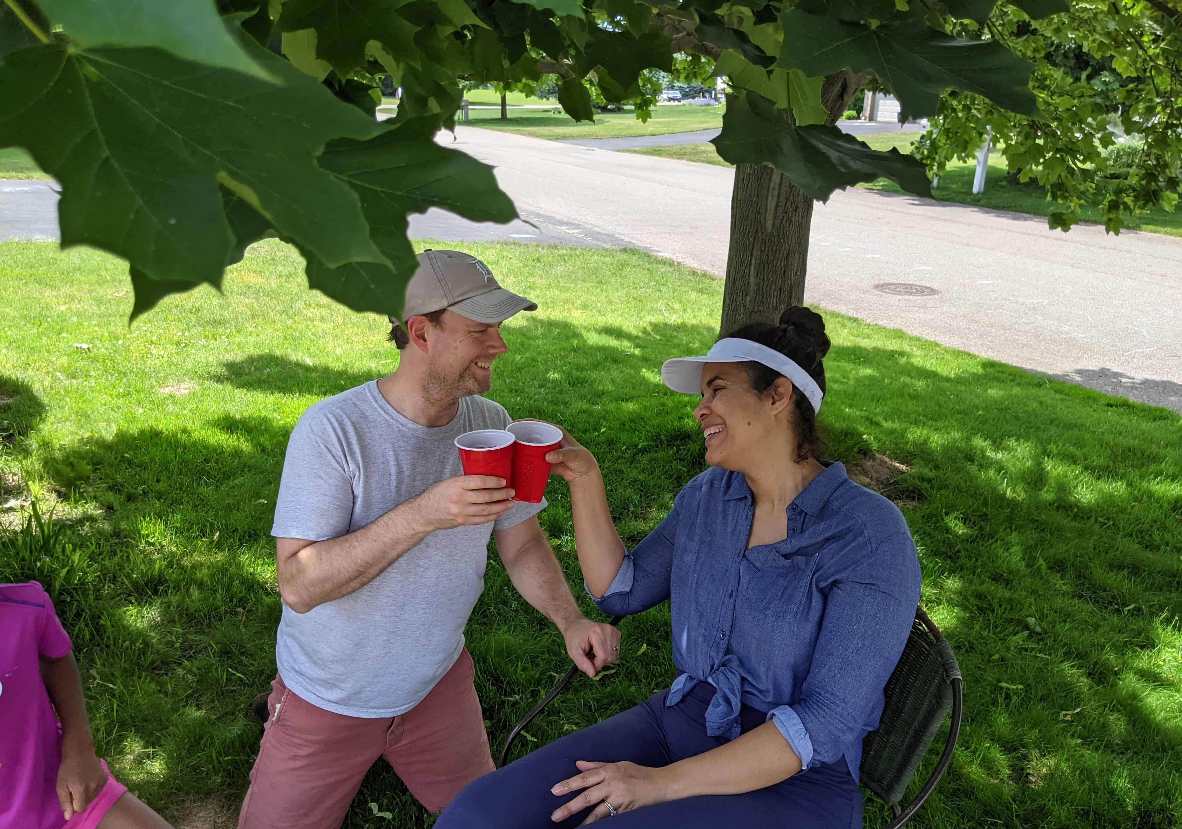 man and woman under a tree toasting
