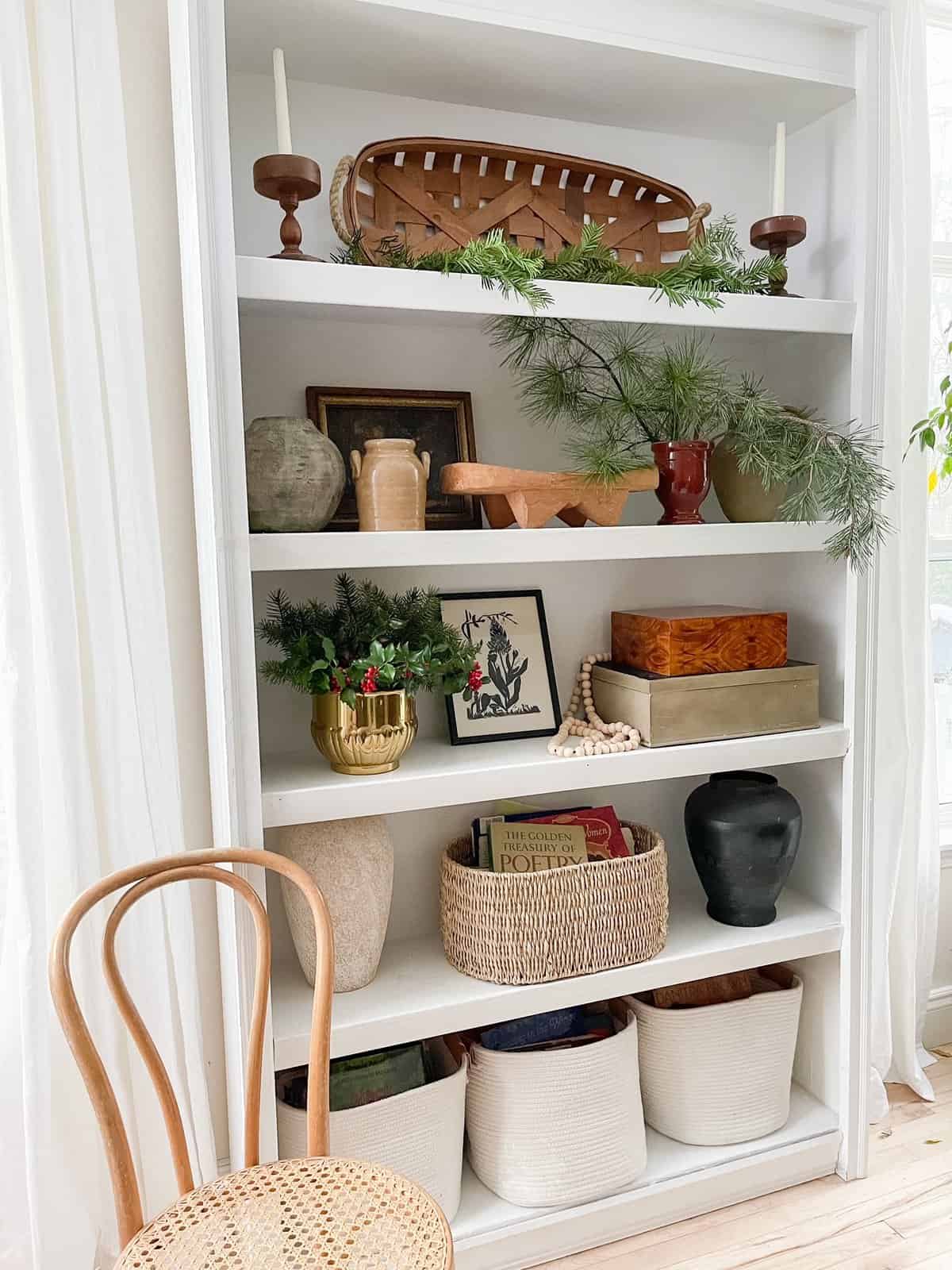 bookshelf styled with evergreens