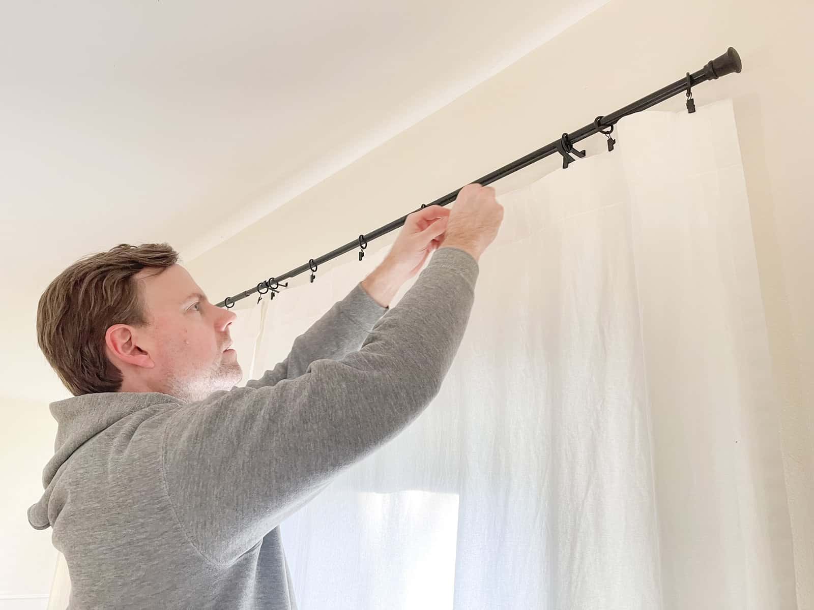 man hanging white curtains