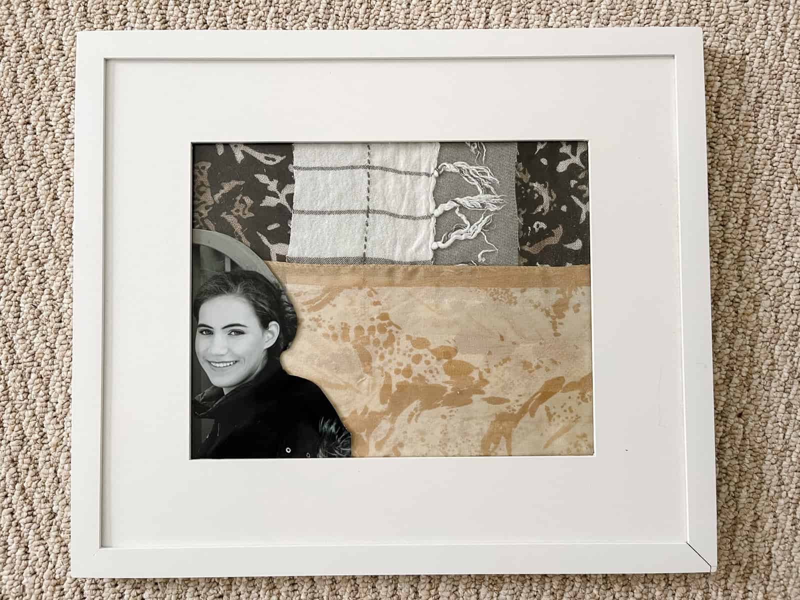 A white picture frame with fabric mat and black and white photo of young woman.