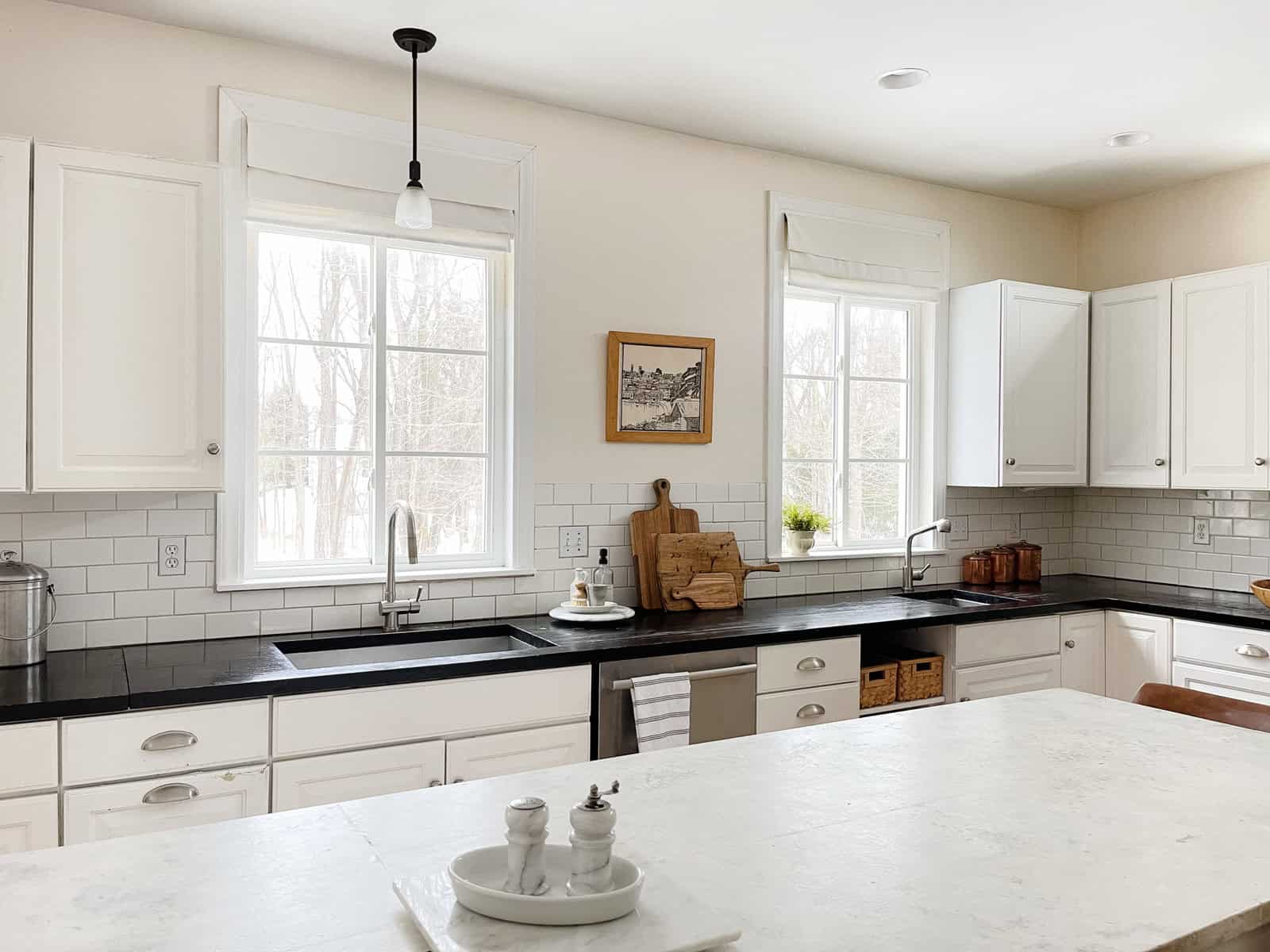 White kitchen cabinets with black counters and two sinks.
