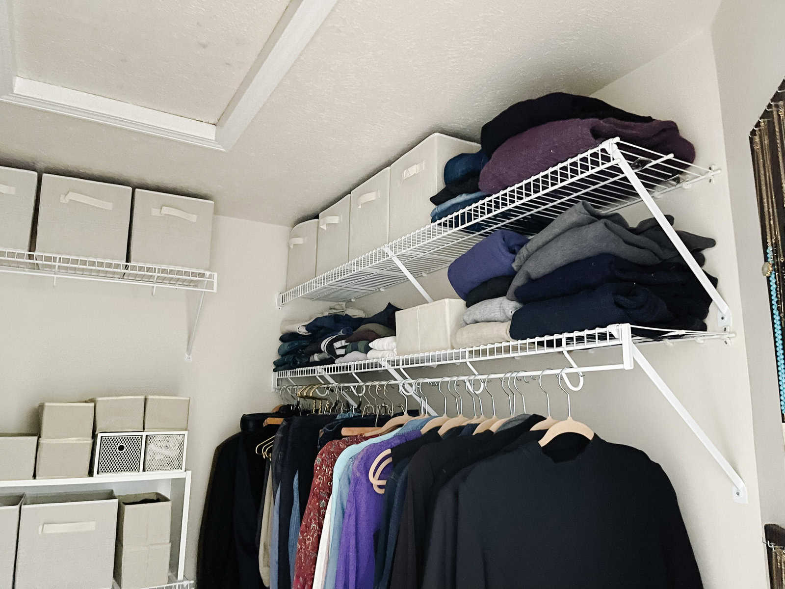 hanging clothes and folded clothing in walk in closet