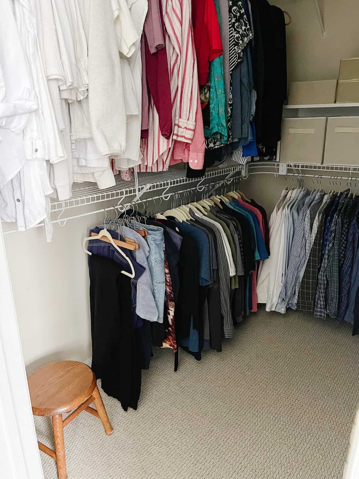 neatly hanging clothes with stool in walk in closet