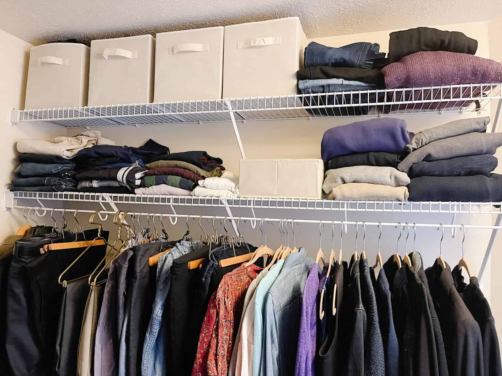 neatly folded and hanging clothes and organization boxes in closet
