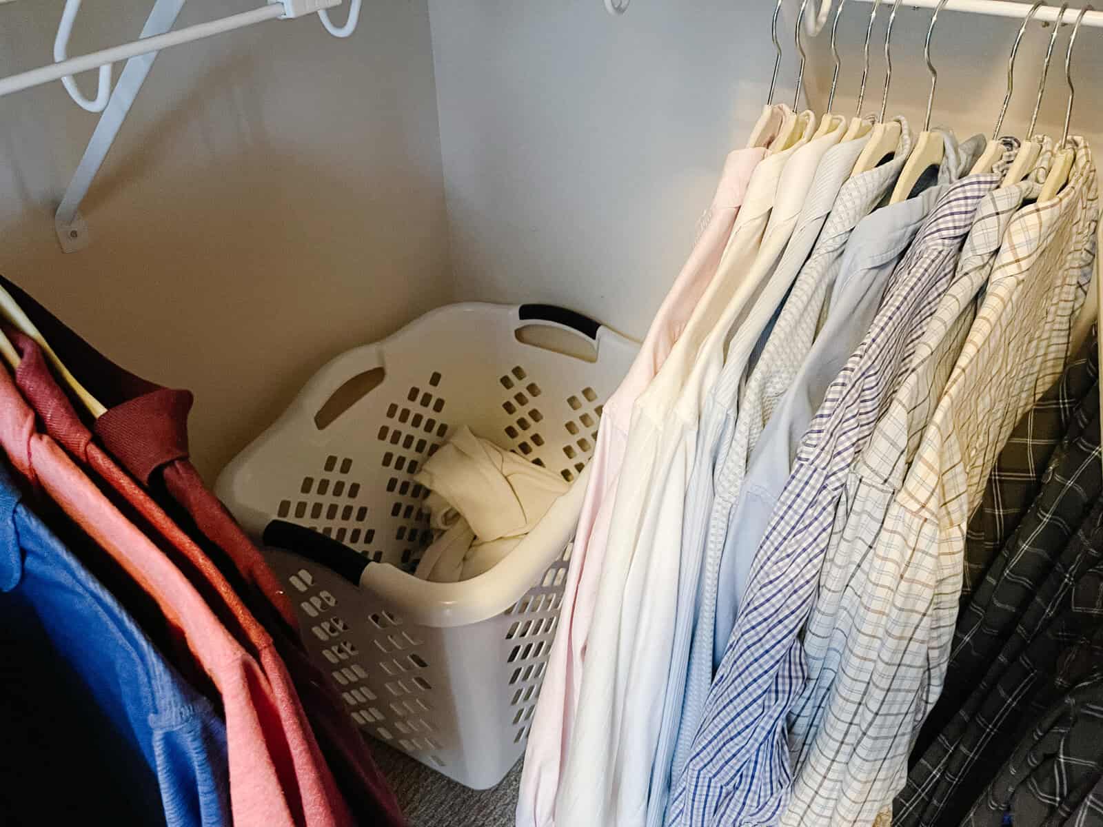 tall laundry basket in corner of organized walk in closet