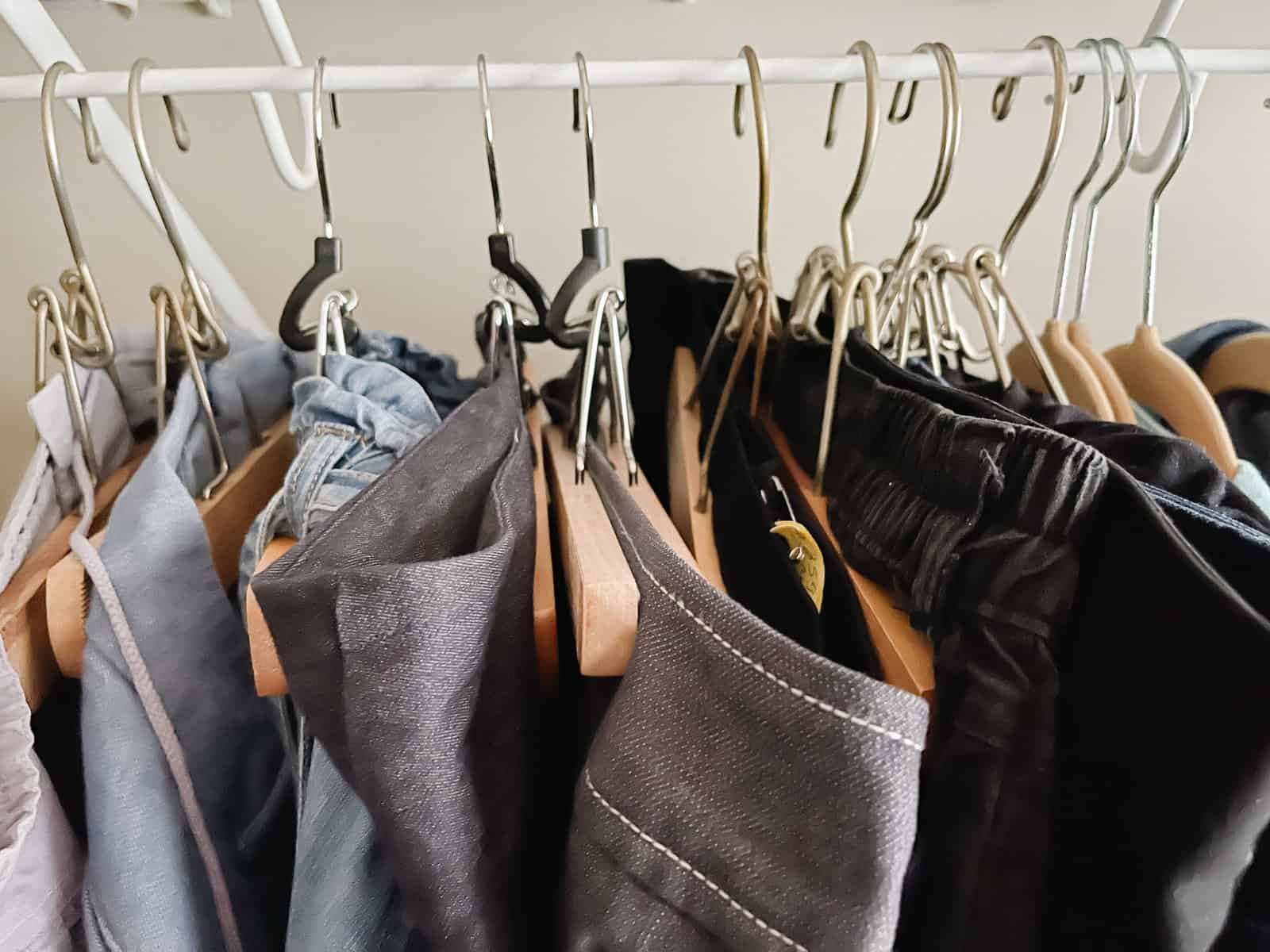 organized pants on wood hangers in closet