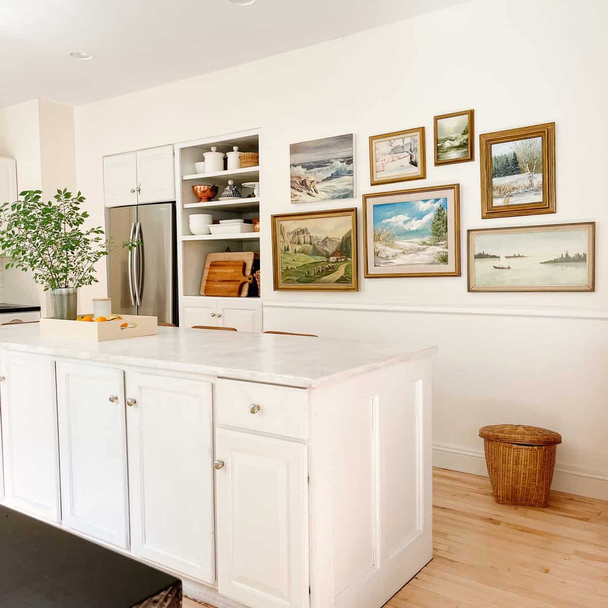 white kitchen with vintage oil paintings on wall