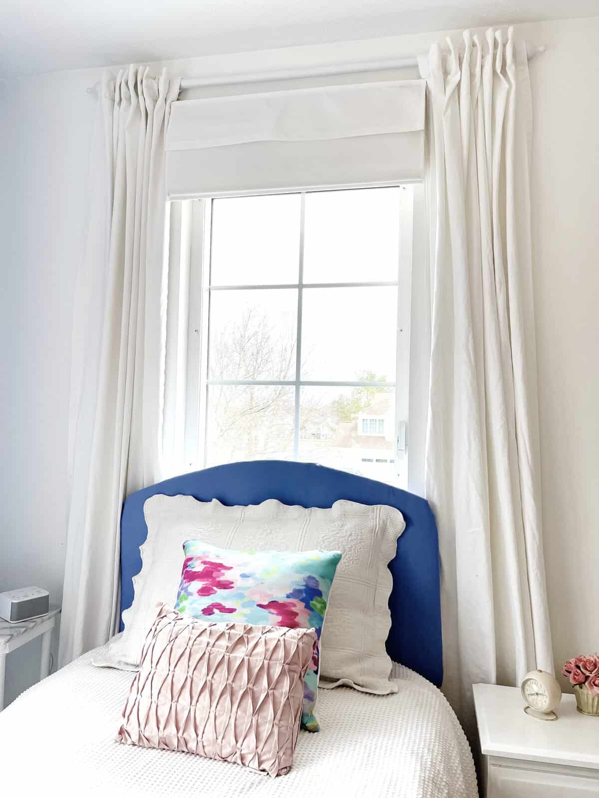 bedroom window over bed with white curtains